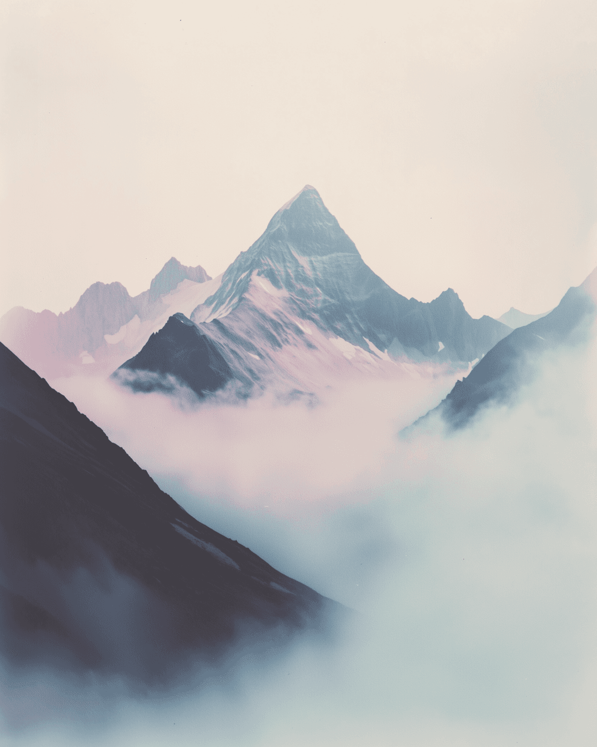 A snow-capped peak rising out of a sea of mist under a pale sky
